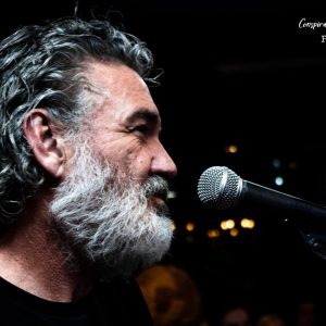 Man with grey hair singing into microphone.