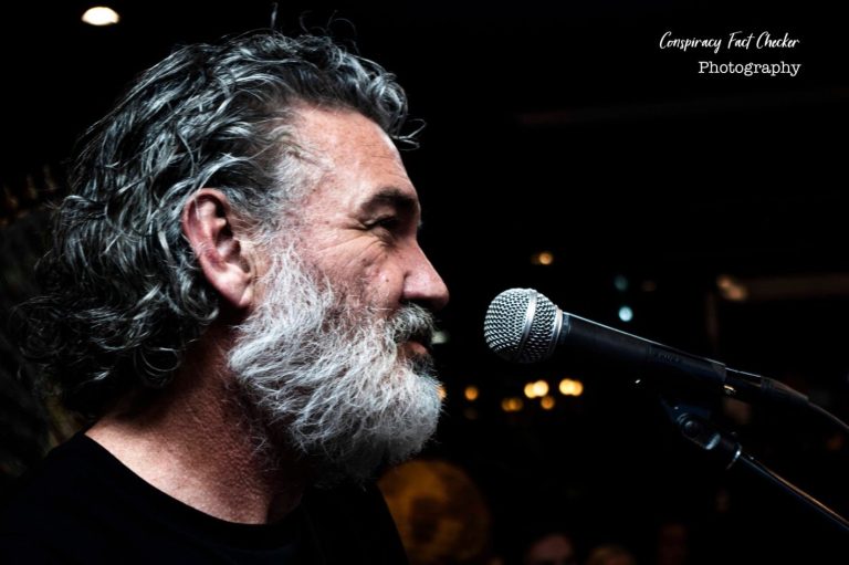 Man with grey hair singing into microphone.