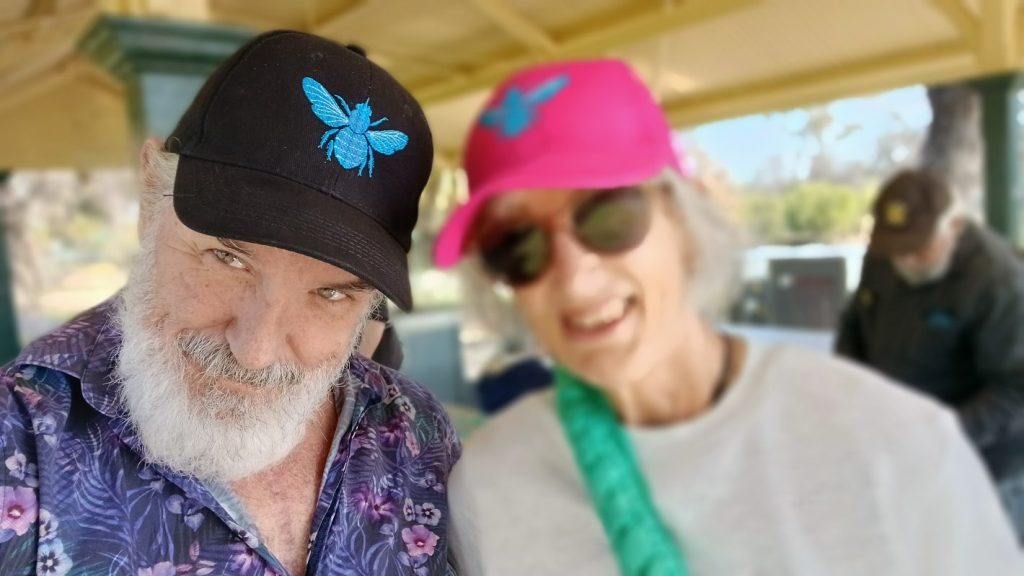 Smiling couple wearing bee embroidered caps.