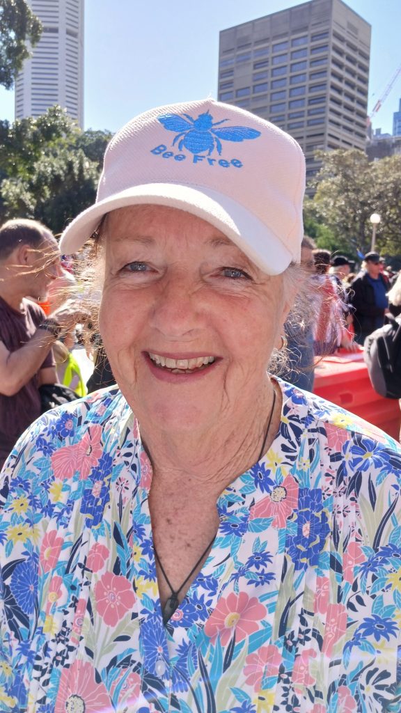 Smiling woman in floral shirt, outdoor event.