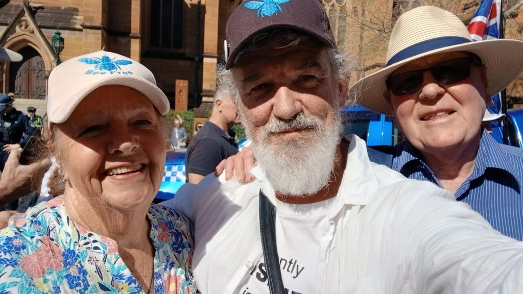 Three people smiling outside church building.