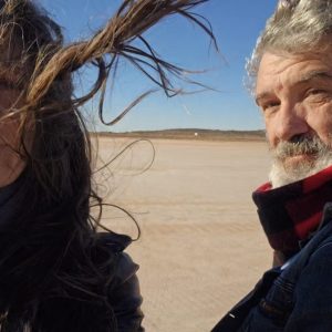 Two people in windy desert landscape.