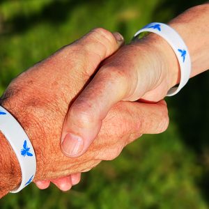 People wearing butterfly wristbands shaking hands outdoors.