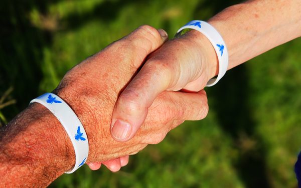 People wearing butterfly wristbands shaking hands outdoors.