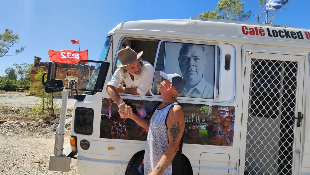Two men shake hands beside Café Locked On van