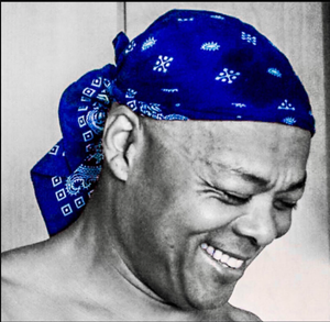 Smiling man wearing a blue patterned bandana