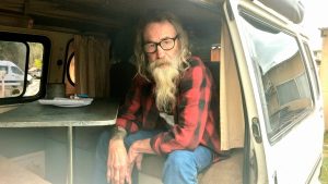 Bearded man seated inside a vintage campervan